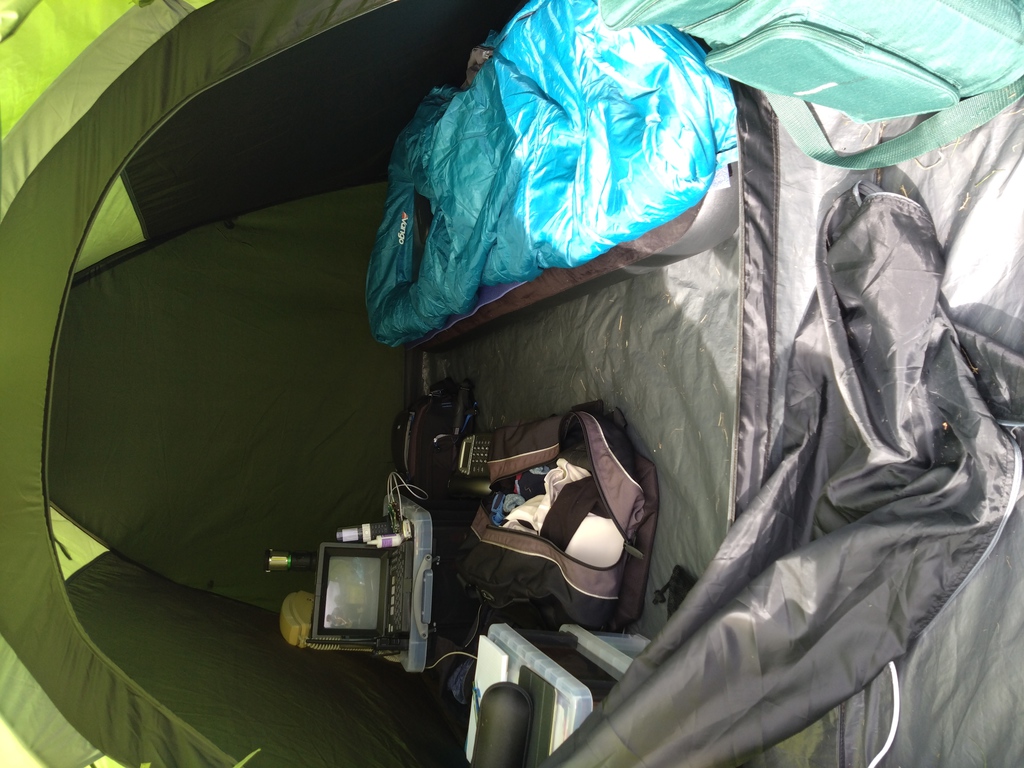 A photograph of the inside of my tent, showing (amongst the usual camping gear etc.) a camera bag, a Viewdata terminal and several telephones.